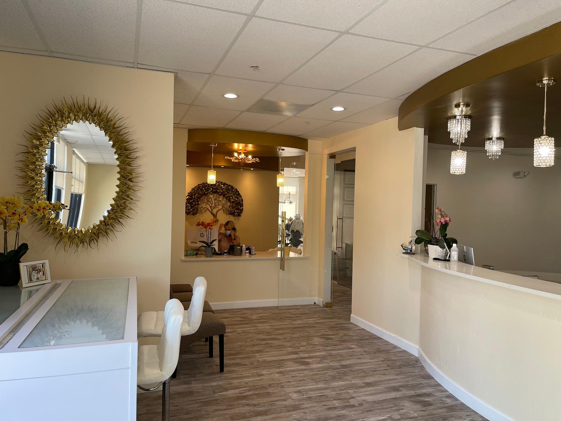 The Creekside Dentistry waiting room — gold sunburst mirror, golden tree mural, and chandelier lighting